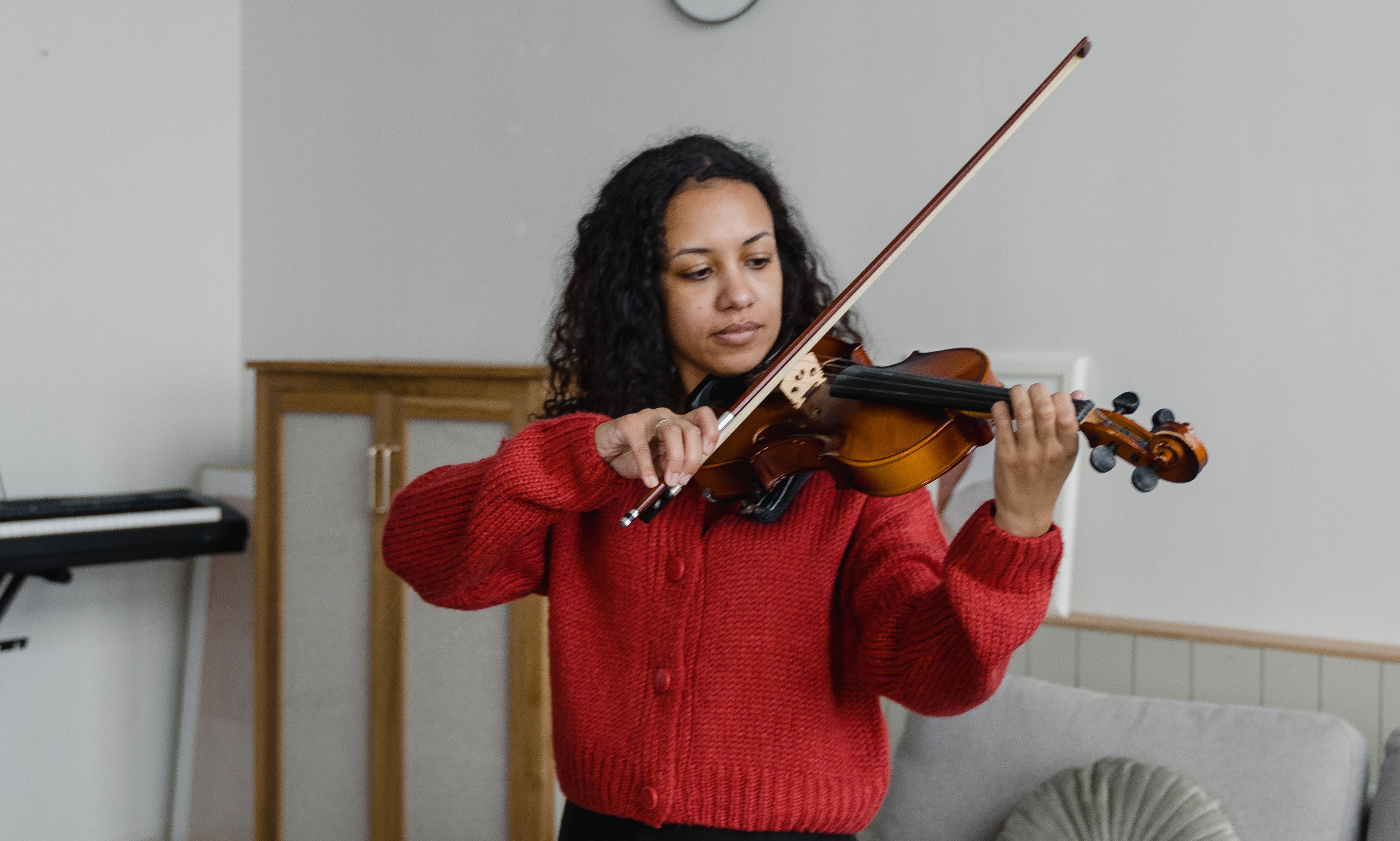 A woman standing playing a fiddle. 