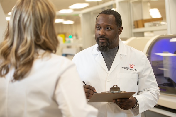 two students talking to each other, both in medical UC coats