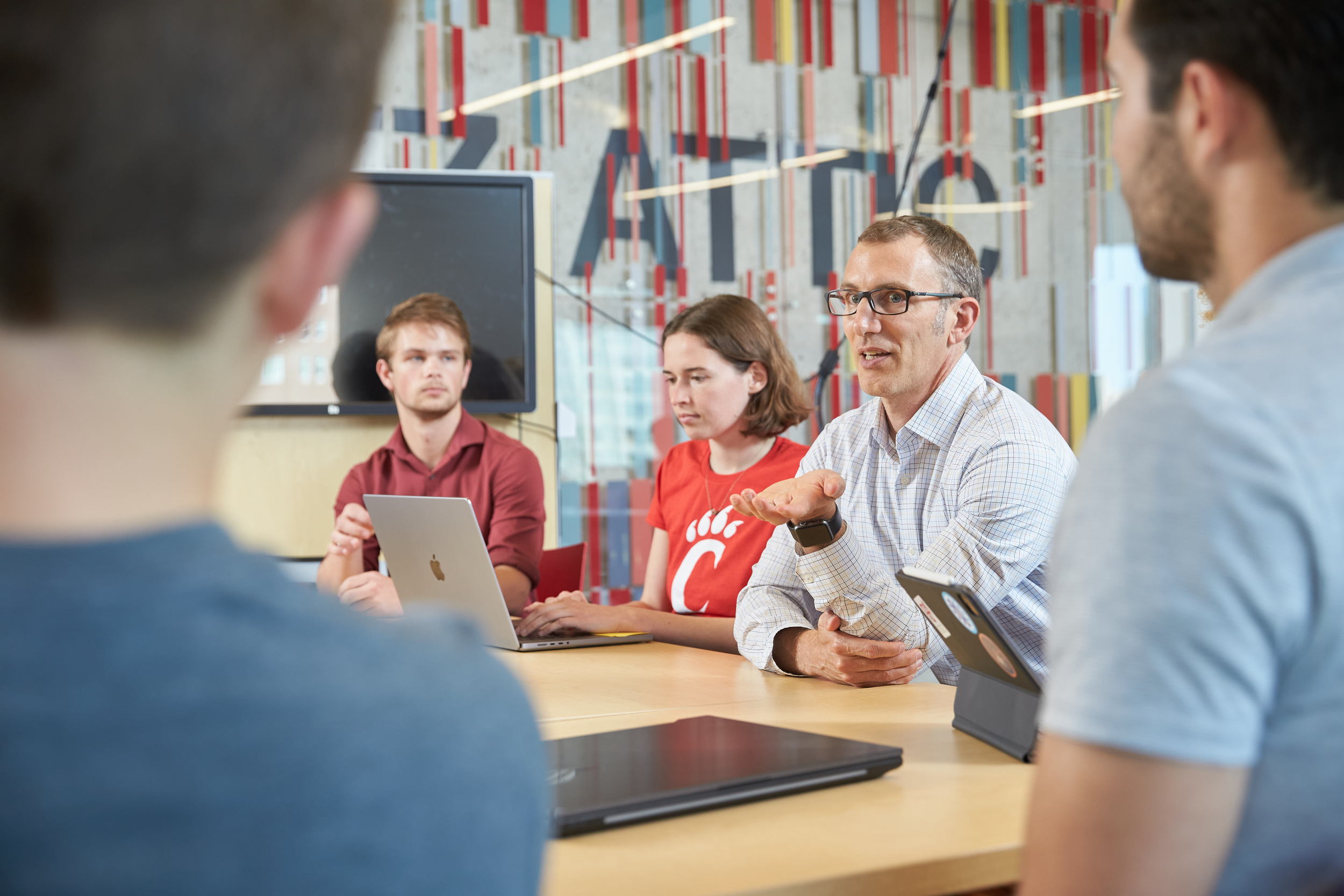 a male teacher stands and leads several students during in discussion